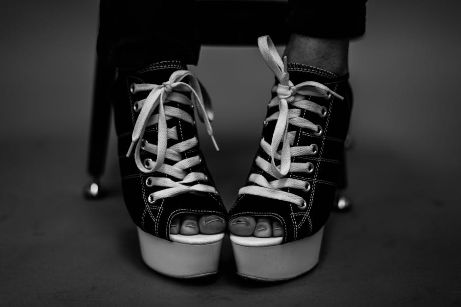 Black and white photo of high-heeled lace-up shoes with open toes, artistic style.