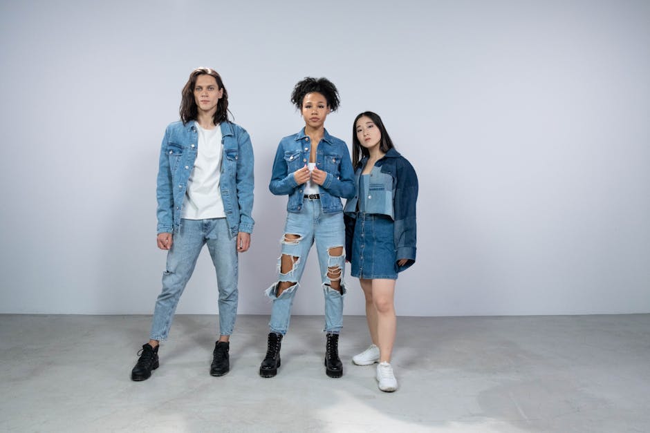 A stylish, diverse group poses in trendy denim outfits against a minimalist backdrop.
