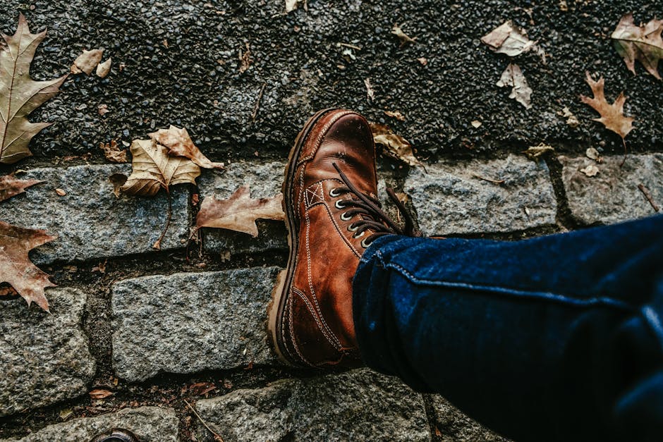A stylish walk in New York with leather boots and denim on a leaf-covered path.