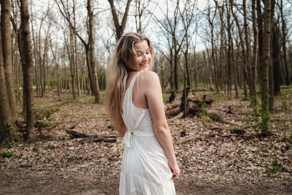 A smiling woman in a white dress enjoys a spring day in the Illinois woods.